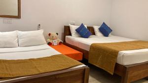 a teddy bear sitting between two beds in a room at Joy Land Resort in Habarana