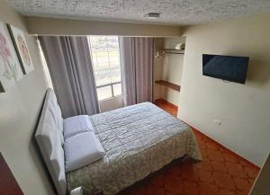 a small bedroom with a bed and a window at Apart colección cusco in Cusco