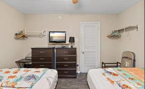 a bedroom with two beds and a dresser with a television at 1 Bedroom Beach Condo with a Pool & Balcony in Wildwood Crest +9 photos