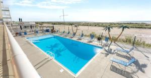a swimming pool with chairs and a beach at 1 Bedroom Beach Condo with a Pool & Balcony in Wildwood Crest