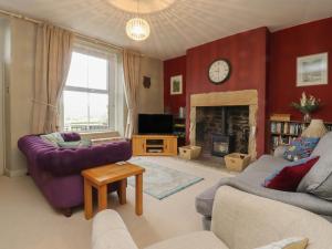 a living room with a purple couch and a fireplace at Canalside Cottage in Kildwick