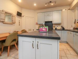 a kitchen with white cabinets and a wooden table at Canalside Cottage in Kildwick