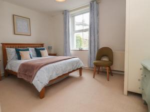 a bedroom with a bed and a chair and a window at Canalside Cottage in Kildwick