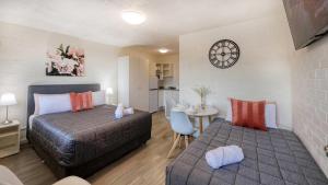 a bedroom with two beds and a table and a clock at AZA Motel in Lismore