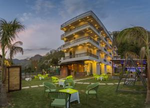 a building with tables and chairs in front of it at Tripli Hotels Sukritham in Narendranagar