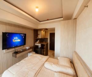 a hotel room with a bed and a flat screen tv at M Apartement in Seturan