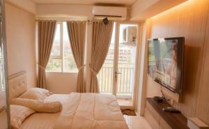 a bedroom with a bed and a tv and a window at M Apartement in Seturan