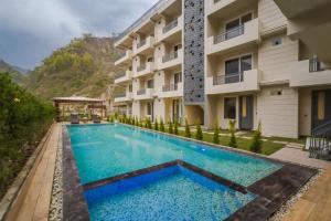an image of a swimming pool in front of a building at Tripli Hotels Sukritham in Narendranagar