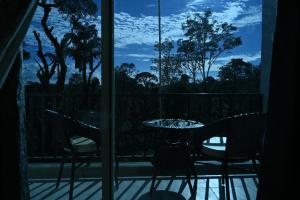 a room with a table and chairs on a balcony at Bougain Villa in Madikeri