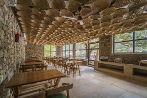 a restaurant with wooden tables and chairs and windows at Tripli Hotels Sukritham in Narendranagar