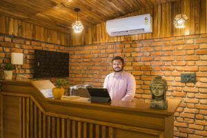 a man standing behind a counter with a laptop at Tripli Hotels Sukritham in Narendranagar +66 photos