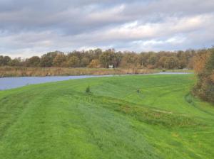 a large green field with a lake in the background at Huis-Meerwijck in Kropswolde +17 photos