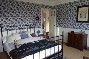 - une chambre avec un lit et du papier peint bleu dans l'établissement La Maison rose, à Portbail