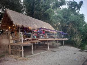 a building with a thatched roof on the side at Champasak Backpacker in Ban Mouang