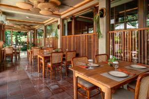 ein Restaurant mit Holztischen und -stühlen und Fenstern in der Unterkunft Ayom Java Village Solo in Solo