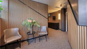 a hallway with two chairs and a table with a vase of flowers at AZA Motel in Lismore