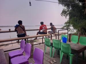 a group of men sitting on a fence near the water at Champasak Backpacker in Ban Mouang +4 photos
