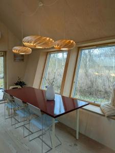 a dining room with a table and two windows at Architectural Tiny House With Sauna Near Beach in Asnæs