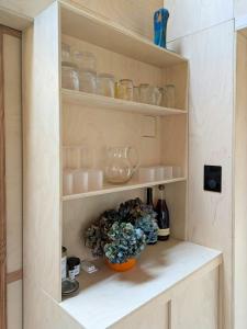 a shelf with dishes and a bowl of flowers at Architectural Tiny House With Sauna Near Beach in Asnæs +15 photos