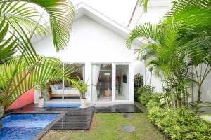 a white house with palm trees and a swimming pool at Polly Canggu 1BR Private Pool Villa By Bali Bliss Properties in Buduk
