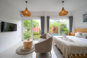 a bedroom with a bed and a chair and a tv at Polly Canggu 1BR Private Pool Villa By Bali Bliss Properties in Buduk