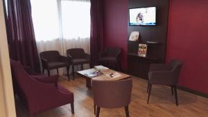 une salle d'attente avec des chaises, une table et une télévision dans l'établissement Hotel Inn Design Poitiers Sud, à Poitiers