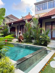 a person sitting in front of a house with a swimming pool at Cempaka Kembar Guest House Ubud in Ubud