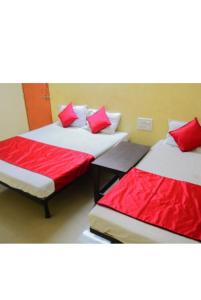 two beds in a room with red pillows on them at Sai Gaurav Palace in Shirdi