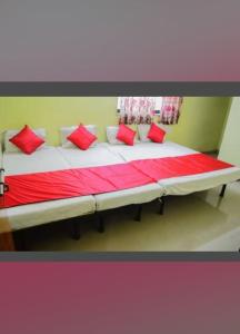 a large bed in a room with red pillows on it at Sai Gaurav Palace in Shirdi