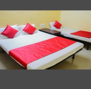 two beds with red pillows in a room at Sai Gaurav Palace in Shirdi