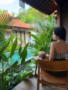 a woman sitting in a chair looking out at a garden at Cempaka Kembar Guest House Ubud in Ubud +61 photos
