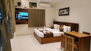 a bedroom with a bed and a table and a television at Dass Paradise Hotel in Bodināyakkanūr