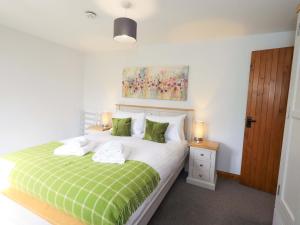a bedroom with a bed with green and white sheets at High Dow Crag in Coniston