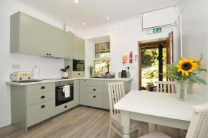 a kitchen with white cabinets and a table with a sunflower at Tor View Fourwinds in Okehampton