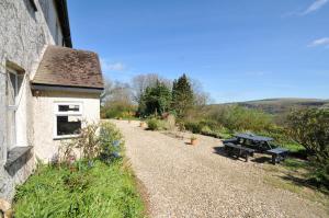 a picnic table next to a building and a gravel road at Tor View Fourwinds in Okehampton