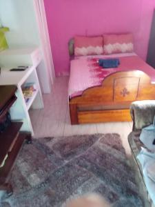 ein Schlafzimmer mit einem Holzbett und rosa Wänden in der Unterkunft Queen room in Bridgetown