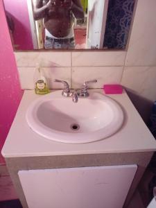 Ein Waschbecken im Badezimmer, vor dessen Spiegel sich jemand fotografiert. in der Unterkunft Queen room in Bridgetown
