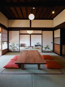 a room with a wooden table and orange cushions at ノキシタ in Hokuto