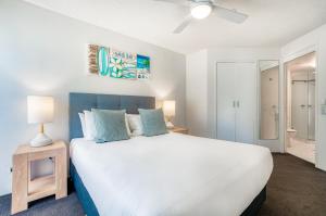 a bedroom with a large white bed with blue pillows at Sailport Mooloolaba Apartments in Mooloolaba
