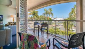 a room with a balcony with chairs and a table at Sailport Mooloolaba Apartments in Mooloolaba