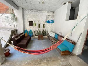 eine Hängematte in einem Wohnzimmer mit Sofa in der Unterkunft GoodWaves Surf Hostel in Huanchaco