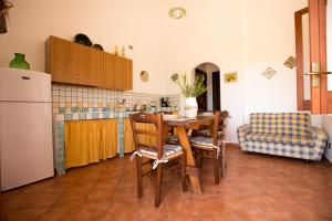 Una cocina con mesa y sillas y un refrigerador. en Villa Chiara, en Scopello