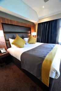 a hotel room with a large bed with yellow pillows at Frensham Pond Country House Hotel & Spa in Farnham
