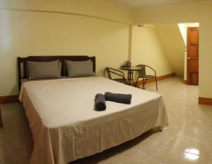 a bedroom with a large white bed and a table at Relax Inn in Ban Phe