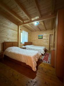 a bedroom with two beds in a log cabin at Eco Camping Valbone in Valbonë