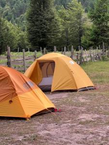 two tents sitting in a field next to a fence at Eco Camping Valbone in Valbonë +19 photos