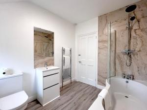 a white bathroom with a tub and a toilet and a sink at Dale View in Youlgreave +18 photos