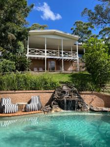 a swimming pool with two lounge chairs in front of a house at Mountain View Blue Mountains in Kurrajong