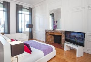 a white living room with a television and a fireplace at L'Esplanade Lille in Lille