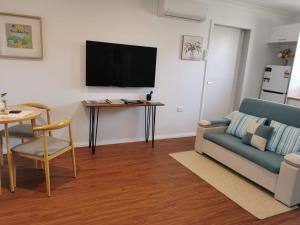 a living room with a couch and a table with a tv at Creekside Cottage - Private Studio with Mountain View in Coffs Harbour
